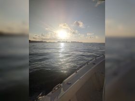 A serene view of the sunset over the water, captured from the deck of a boat, showcasing the tranquil beauty of a boating experience.