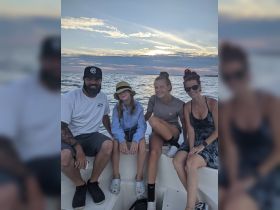 A joyful family enjoys a sunset on the water, capturing a memorable moment aboard their boat — perfect for family outings and celebrations.