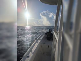 A child enjoys the ocean view from the boat as the sun shines brightly overhead, capturing a serene moment on the water.