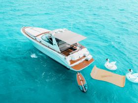 A stunning aerial view of a luxurious yacht cruising through crystal-clear turquoise waters, showcasing its elegant design and inviting deck space.