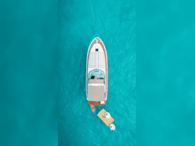 Aerial view of a sleek boat anchored in crystal-clear turquoise waters, showcasing its elegant design and inviting atmosphere for a perfect day on the water.