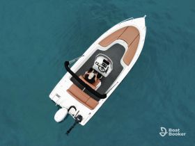 Aerial view of a sleek speedboat cruising through clear waters, showcasing its stylish design and comfortable seating.