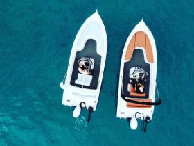 Aerial view of two boats on clear turquoise waters, showcasing individuals enjoying a day on the water — perfect for adventure seekers and boating enthusiasts.