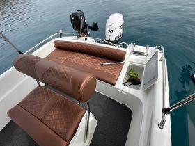 Interior view of a stylish boat seating area featuring plush, quilted seats and a well-equipped console, perfect for comfortable outings on the water.