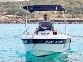 A man navigates a rental boat through crystal-clear waters, showcasing the perfect opportunity for a day of adventure on the sea.