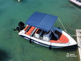 A sleek speedboat docked in clear turquoise waters, showcasing its vibrant seating and canopy — perfect for a day on the water.