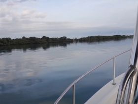 A serene view of a calm waterway bordered by lush greenery, perfect for showcasing the tranquility of a boating experience.
