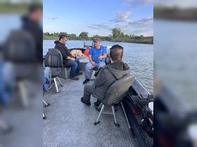 A group of friends relaxes on a boat, enjoying a day on the water with a dog lounging nearby — perfect for fishing trips or leisurely outings.