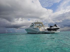A stunning yacht anchored in crystal-clear waters, showcasing its sleek design against a backdrop of dramatic clouds — perfect for luxury boating experiences.
