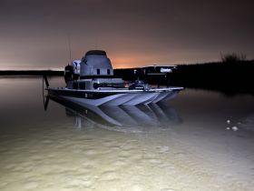 A sleek boat is docked in calm waters at night, reflecting the serene ambiance of the surroundings — perfect for nighttime fishing or leisurely outings.