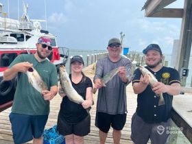 A group of friends proudly displays their catch after a successful fishing trip, showcasing the joy of fishing adventures on the water.