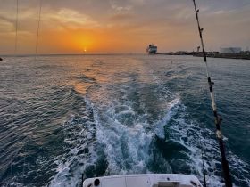 A stunning sunset over the ocean, viewed from a boat, creating a picturesque backdrop for a serene cruise experience.