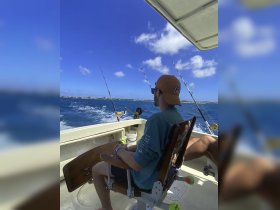 A fisherman relaxes in a chair aboard a boat, enjoying a day of fishing on the open ocean — a perfect escape for fishing enthusiasts.