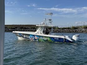 A vibrant speedboat named 'Stoked on Fishing' cruises through the water, showcasing its sleek design and fishing capabilities.
