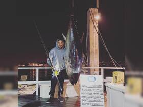 An angler proudly displays a massive bluefin tuna caught during a night fishing trip aboard the Miss Parker — a thrilling catch that showcases the excitement of deep-sea fishing.