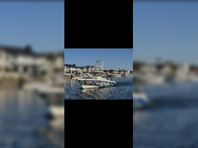 A vibrant speedboat named 'STOKED FISHING' cruises through calm waters, showcasing its colorful design against a picturesque waterfront backdrop.