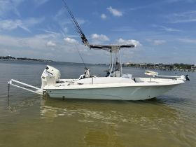 A sleek speedboat is docked in calm waters, showcasing its design against a picturesque backdrop of blue skies and distant shorelines.