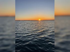 A stunning sunset over calm waters, creating a picturesque scene perfect for evening boat cruises or romantic getaways.