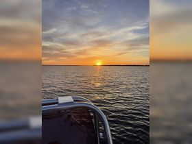 A serene sunset view from a boat, capturing the vibrant colors reflecting on the water — perfect for peaceful evening cruises.