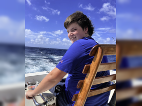 A young boy enjoys a day of fishing on the open ocean, showcasing the joy of boating adventures and the thrill of the catch.