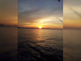 A stunning sunset over calm waters, captured from a boat, creating a picturesque backdrop for evening cruises.
