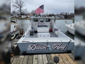 A rear view of the 'Ditch Hag' fishing boat docked at Sparrows Point, MD, showcasing its spacious deck and American flag.