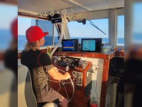 A young person navigates the helm of a boat, showcasing the modern console and electronics — perfect for those learning the ropes of boating.