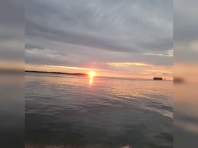 A stunning sunset over calm waters, showcasing the serene beauty of the coastline — perfect for romantic evening cruises or peaceful reflections on the water.