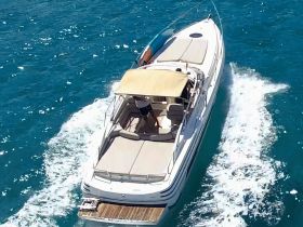 Aerial view of a sleek speedboat cruising through vibrant blue waters, showcasing its elegant design and underway motion.