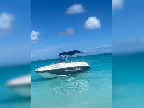 Two individuals enjoy a sunny day aboard the 'SeaLicious' boat, surrounded by stunning turquoise waters — a perfect setting for a day of adventure on the ocean.