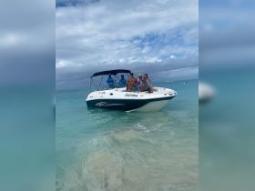 A cheerful group poses on their boat, 'Sealicious,' enjoying a fun day at the beach — perfect for memorable outings and celebrations on the water.