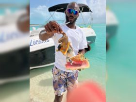 A man showcases freshly caught conch and seafood, perfect for a culinary adventure on the water. Enjoying the vibrant marine life while snorkeling adds to the experience.