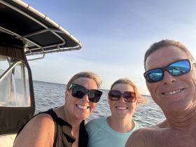 A cheerful group enjoys a boat ride, capturing a memorable moment with smiles against a beautiful water backdrop.