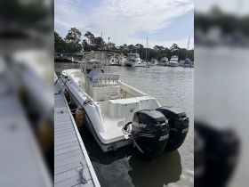 A center console boat is docked at the marina, showcasing its sleek design and powerful twin engines, perfect for fishing or cruising.