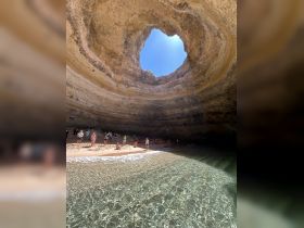 Visitors enjoy a stunning beach inside a cave, with clear waters and kayaks visible, making it a perfect spot for adventure and exploration.