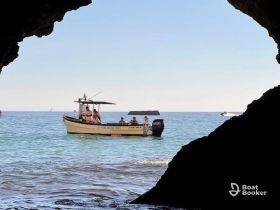 A scenic view of a boat with guests enjoying a tour, framed by a natural cave entrance — perfect for exploring coastal beauty and marine adventures.