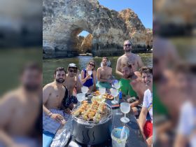 A lively group enjoys a barbecue on a boat, surrounded by stunning rock formations — perfect for summer gatherings and celebrations on the water.