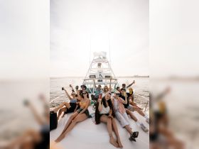 A lively group celebrates aboard a yacht, raising their drinks in a toast against a beautiful backdrop — perfect for unforgettable party experiences on the water.