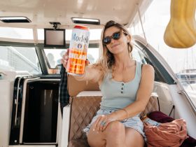 A woman enjoys a refreshing Modelo Chelada while relaxing inside a stylish boat, showcasing the perfect ambiance for a day on the water.