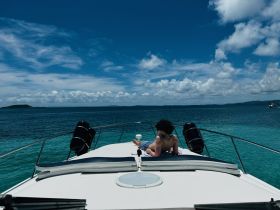 A child relaxes on the bow of a boat, enjoying the sunny ocean view — a perfect moment for family adventures on the water.