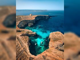 A stunning aerial view of a secluded cove with crystal-clear turquoise waters and boats anchored, showcasing the natural beauty of the coastline.