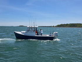 A fishing boat navigates through the water with anglers on board, showcasing an exciting day of fishing adventures.