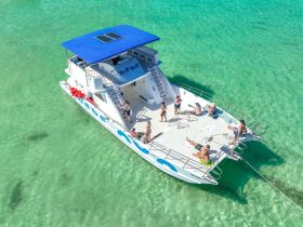 A lively group enjoys a day on the water aboard a spacious boat, surrounded by stunning turquoise waters — perfect for summer fun and aquatic adventures.