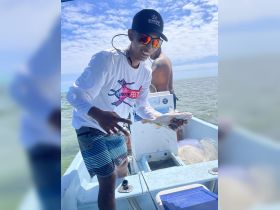 A smiling angler proudly displays his catch aboard a fishing boat, showcasing the excitement of a day on the water.