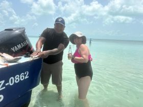 A joyful moment as two guests celebrate their fishing catch at a beautiful beach, with clear waters and a relaxed atmosphere perfect for a day of fun.