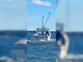 A fishing boat named 'Grace' navigates through the water, showcasing its structure and design while underway.