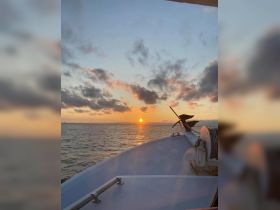 A serene sunset view from the bow of a boat, showcasing the tranquil waters and colorful sky — perfect for evening cruises.