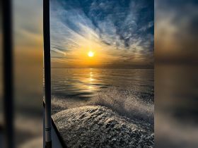 A stunning sunset view from a boat, showcasing the tranquil waters and the shimmering reflection of the sun — perfect for evening cruises.