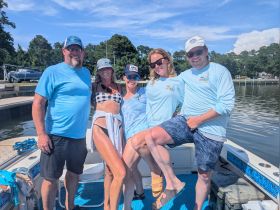 A cheerful group of friends poses on a boat, enjoying a sunny day on the water — perfect for creating unforgettable memories together.