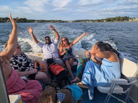 A lively group enjoys a fun day on the water, celebrating with friends and a dog aboard a boat — perfect for memorable outings and adventures.